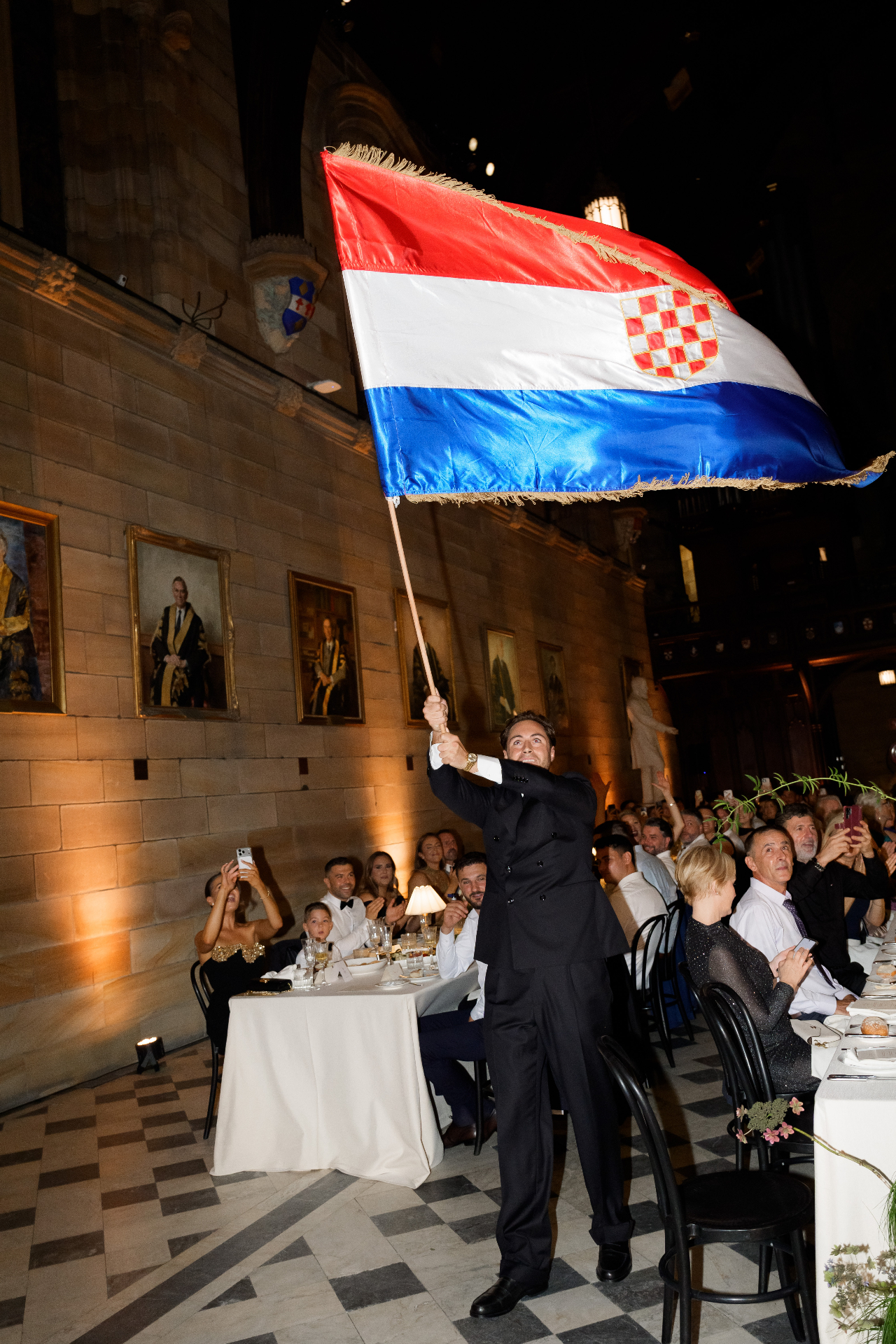 Groom waving the Croatian barjak above guests at a wedding reception